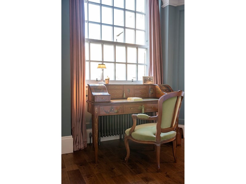 An antique bureau under a window offers plenty of natural light for a spot of work or letter writing.