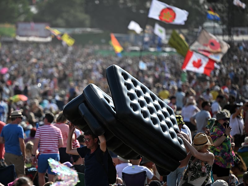 Festivalgoers carry an inflatable sofa on day 3 of the Glastonbury festival. (Photo by OLI SCARFF/AFP via Getty Images)