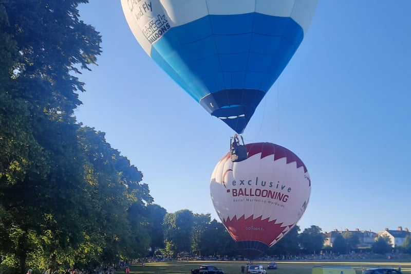 One balloon takes off as another prepares to go as crowds of people watch on inside the park (Photo credit: Chris Ward)
