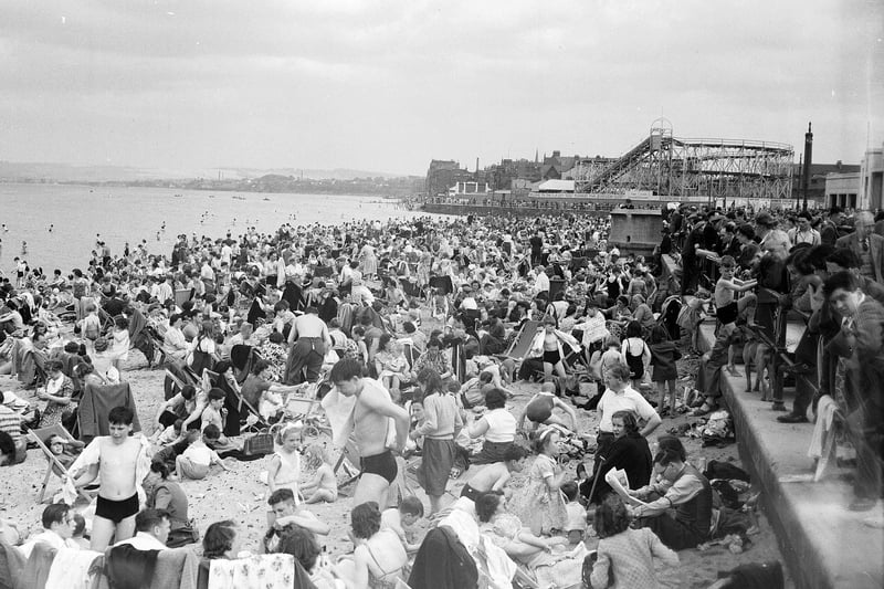 Crowds of holiday-makers on Portobello Beach in 1952 with rollercoaster and funfair in the background.