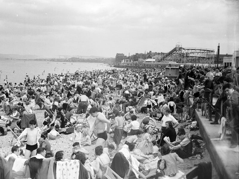 Crowds of holiday-makers on Portobello Beach in 1952 with rollercoaster and funfair in the background.
