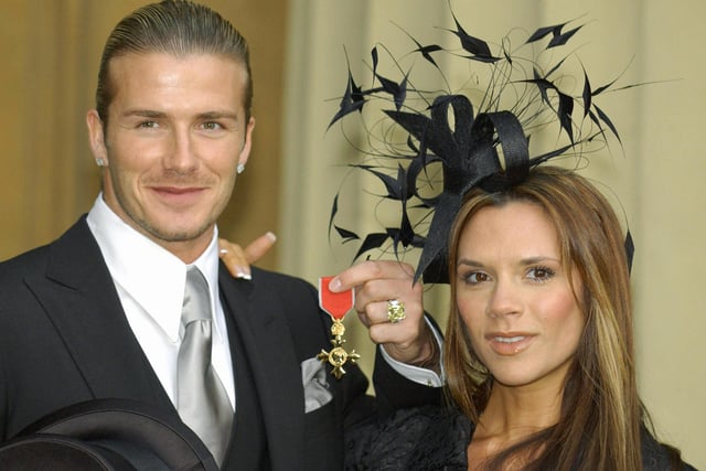 England's football captain David Beckham stands with his wife, Victoria, as he shows off the OBE (Officer of the Order of the British Empire) he received 27 November, 2003, from Britain's Queen Elizabeth II at London's Buckingham Palace. 