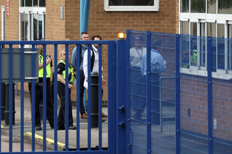 Police can be seen with staff members behind the school gates