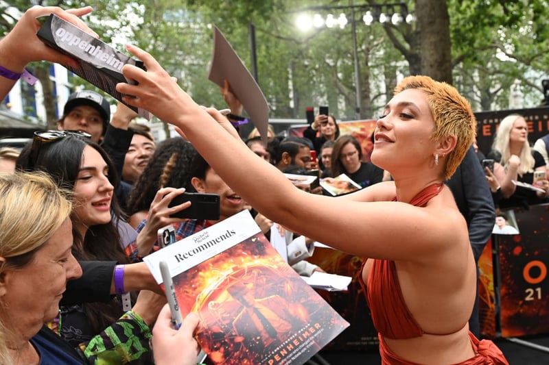 Florence Pugh signs autographs for fans as she arrives at the premiere.