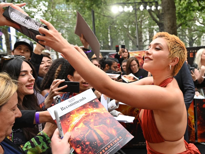 Florence Pugh signs autographs for fans as she arrives at the premiere.