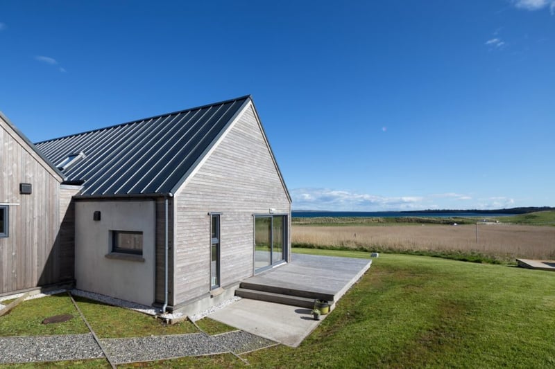 The longhouse is positioned low on a hillside, just above a sandy beach on the coast of the stunning island of Lewis.