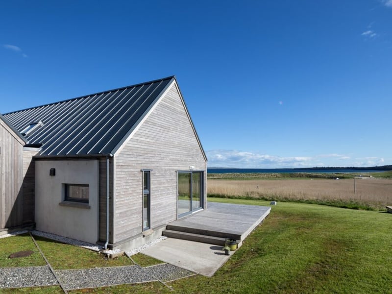 The longhouse is positioned low on a hillside, just above a sandy beach on the coast of the stunning island of Lewis.