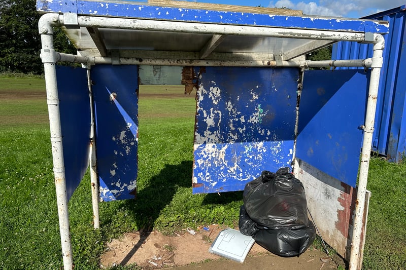 A wooden panel at the back of the sports pitch dugout appears to have been sawn off