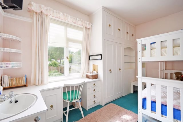 This smaller room is perfect for kids, with a bunkbed, sink, lots of storage, and window-facing desk.