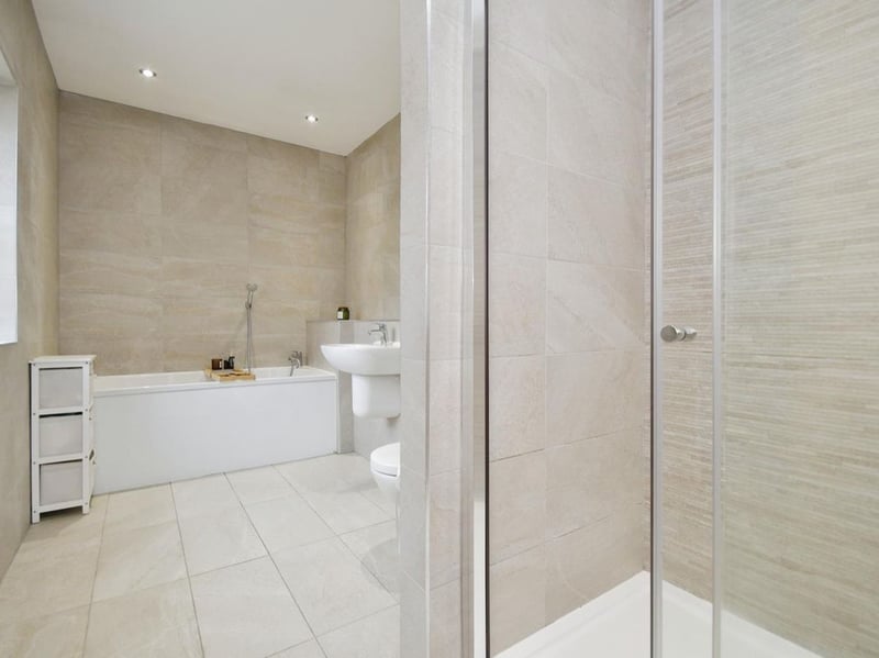 The main family bathroom is spacious and bright, with a shower and bath against the opposite wall.