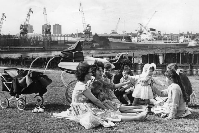 Under the shadow of the ships and cranes of Swan Hunters shipyard, a Hebburn family enjoy a picnic in the King George playing fields in 1964.