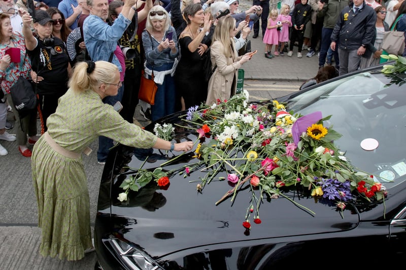 People lay flowers and tributes on the hearse during the funeral procession of late Irish singer Sinead O'Connor, outside the former home in Bray, eastern Ireland. (Photo by PAUL FAITH/AFP via Getty Images)
