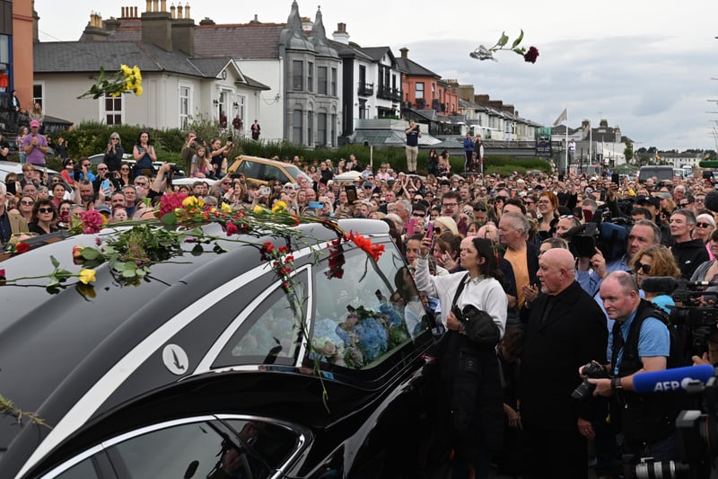 Crowds of people throw flowers as they line the street as the hearse carrying Sinead O’Connor’s coffin passes by her former home on the seafront in Bray, Ireland.  (Photo by Charles McQuillan/Getty Images)