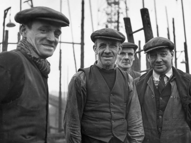 Four workers from the Harland & Wolff Shipyard flash a rare smile at the camera in 1955. The company acquired and amalgamated the London & Glasgow Engineering & Iron Shipbuilding Co.'s Middleton and Govan New Yards, along with Mackie & Thomson's Govan Old Yard, to create a large shipyard specialising in tankers and cargo ships.