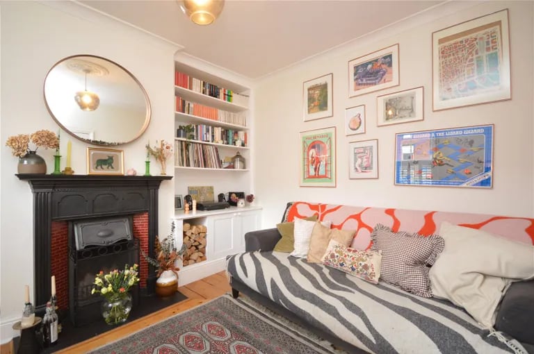 The living room features bespoke alcove cupboards and shelves and a cast iron fireplace.