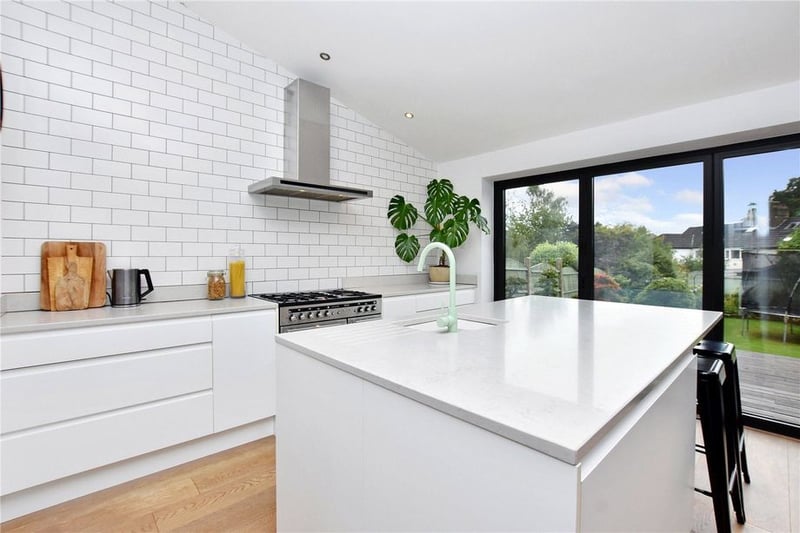The impressive kitchen features a large island with quartz worktop and a mint green tap.