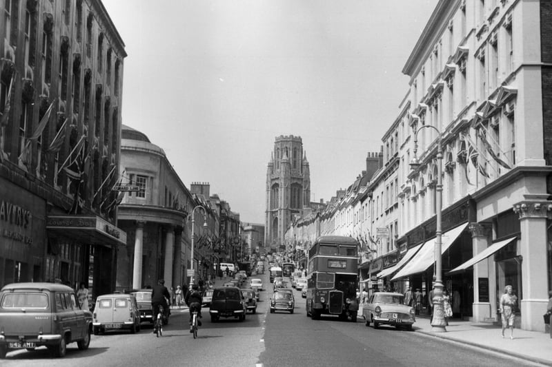 This picture from 1962 shows a whole range of transport coming up and down the shopping street with cars, buses and bicycles pictured. Shoppers, meanwhile, browse the many shops lining the road. 