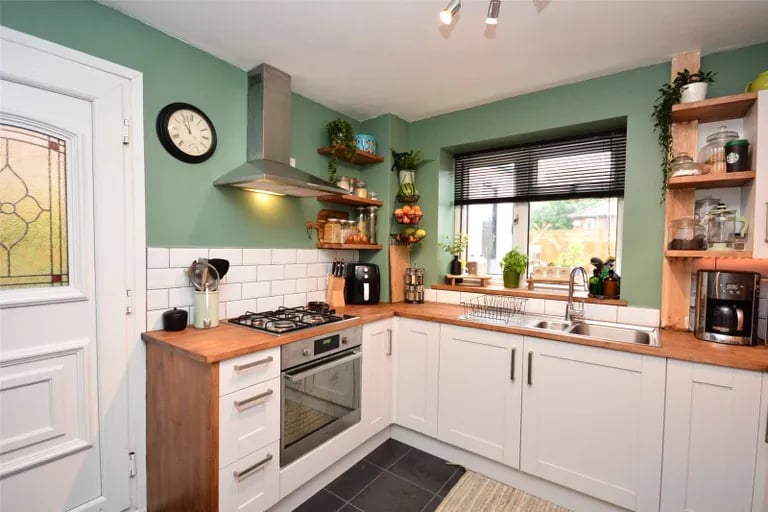 The beautiful kitchen with contemporary grey shaker-style fitted units with solid wood work surfaces over, electric oven, gas hob, space for both a dishwasher and washing machine, open pantry with room for a fridge and storage area, tiled floor and door out to the side elevation.