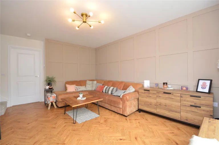 Oak flooring and panelled walls decorate the living room.