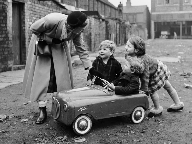 Miss Peggy Robertshaw stops to talk to three children in 1965 as she walks her daily 12 miles around Liverpool, testing shoes. Peggy worked for Dunlop of Speke, and since 1927 had covered over 72,000 miles.