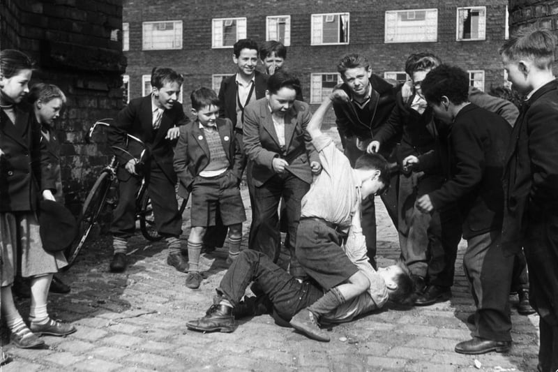 Boys scrambling beside blocks of housing in Liverpool. They are members of the Rodney Youth Centre, known as ‘The Street Corner With A Roof’.