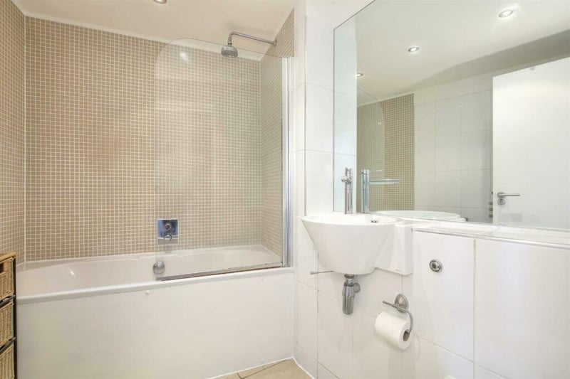 The bright, spacious bathroom has a bath and overhead shower.
