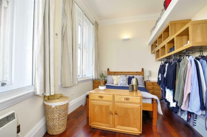 The cosy bedroom, with wooden floors and furniture, has the potential for creative storage solutions such as these exposed clothes rails.