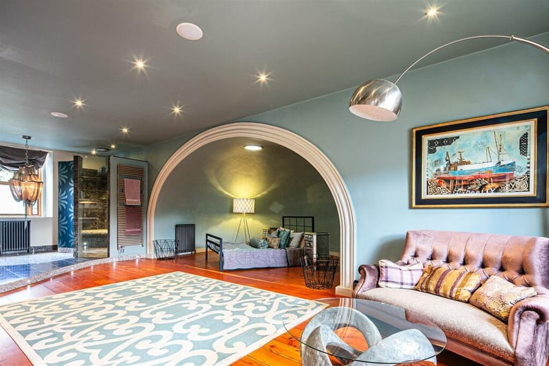 This bedroom on the first floor is the biggest in the house, with a sofa, large open space, and archway through to the bed. 