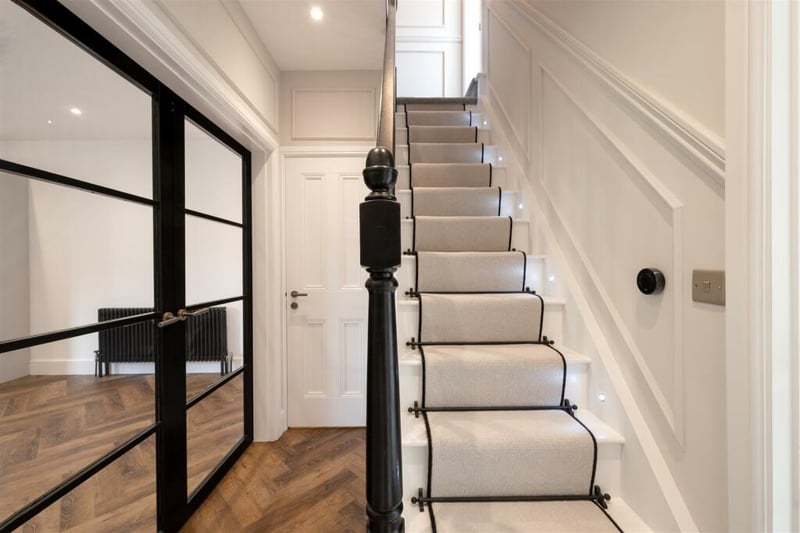 The entrance to the home creates an immediate impression, with a modern carpet runner, LEDs, and decorative rods on the stairs.