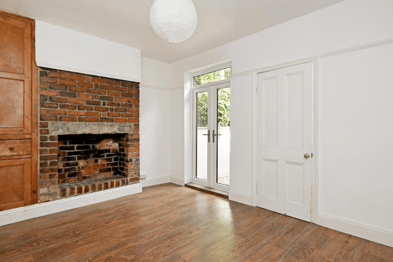 The spacious dining room is naturally lit, thanks to patio doors leading into the garden, and features exposed brick and wooden storage spaces.