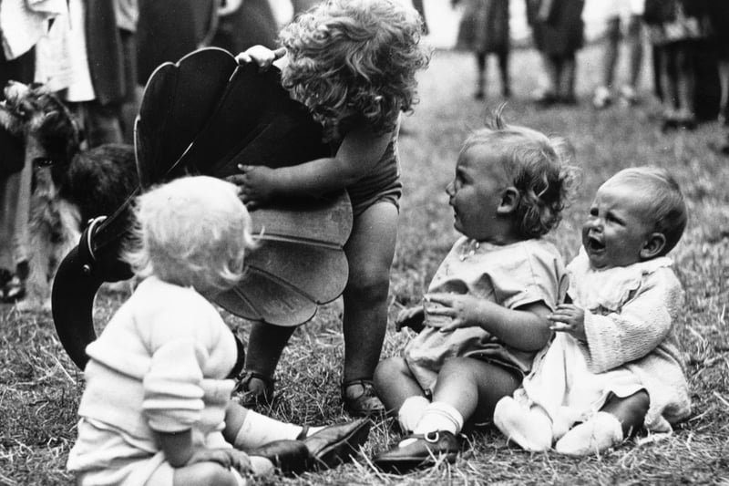 A toddler and three babies, who are contestants in a baby show, investigating a loudspeaker at the annual carnival in Fishponds. Picture was taken on July 23 in 1932.