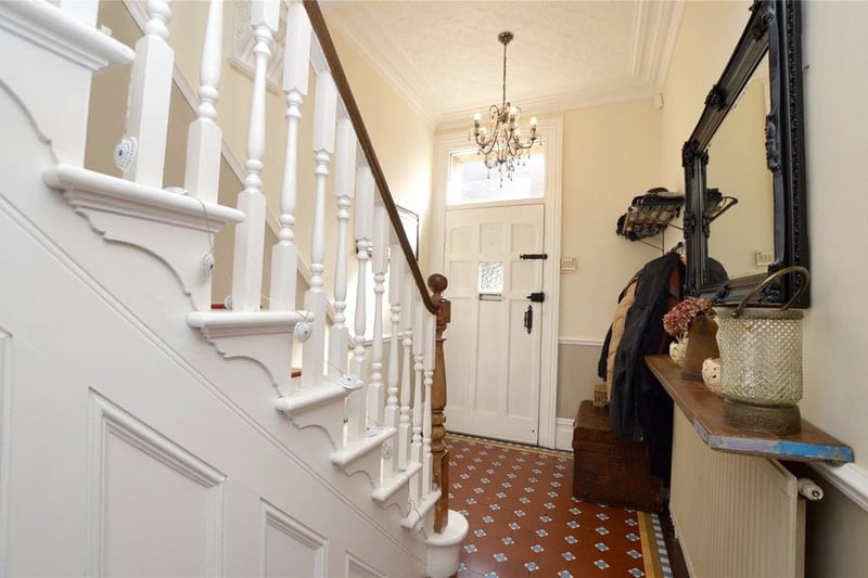 A welcoming entrance hall with original decorative tiled flooring and oak panelled staircase.
