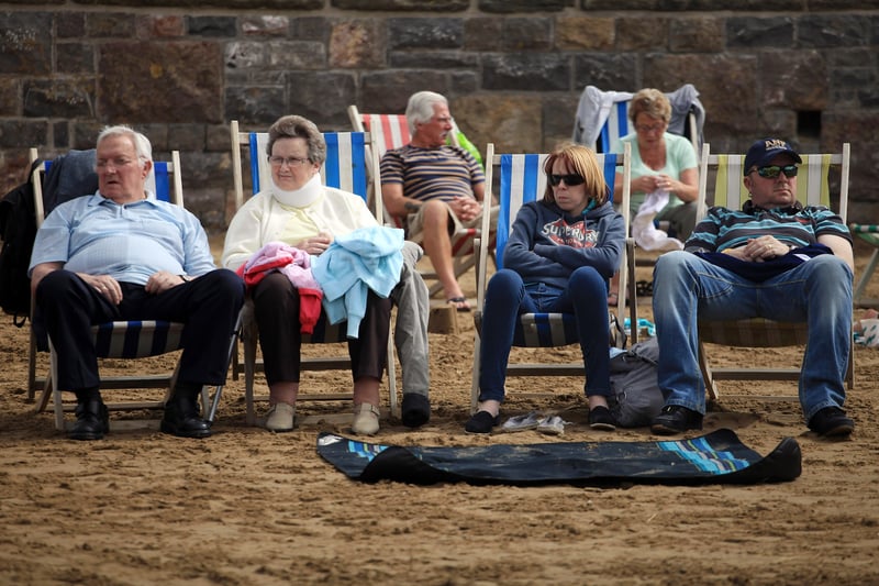 People dressed for all weathers sit in deck chairs on the beach in August 2011. (Photo by Matt Cardy/Getty Images)