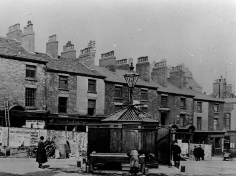 Shops on Barker's Pool, Sheffield, known as Pool Place, prior to demolition in preparation for the War Memorial. The 'Iron Man' public lavatory is also visible in this photo from 1923
