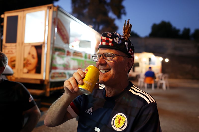 A fan of Scotland is seen drinking outside the stadium.