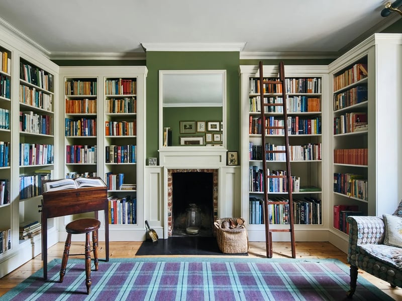The spectacular library with muted green walls and an open fire place 