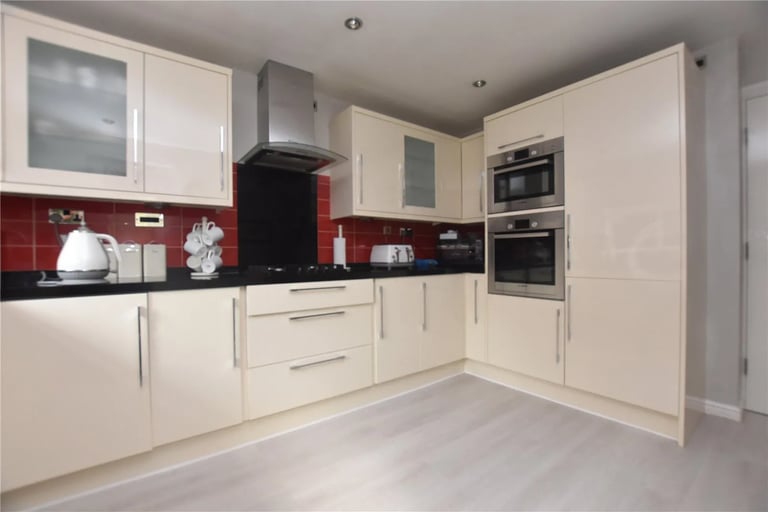 A modern kitchen fitted with a range of wall and base units as well as built in appliances.