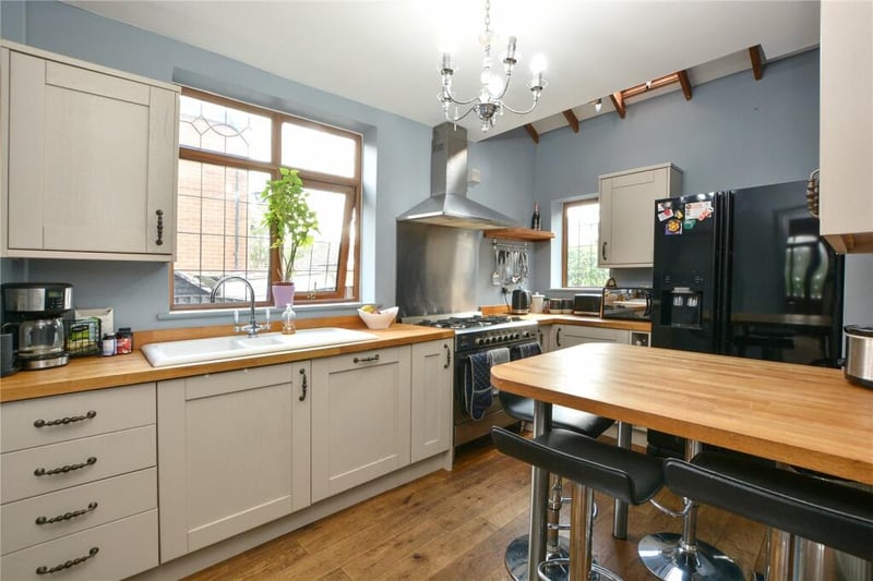 The open plan kitchen area has  a range of mink shaker-style fitted units with solid wood work surfaces over