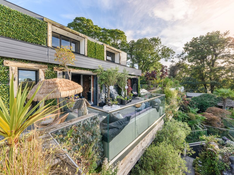 The balcony overlooks a luscious space littered with plants and tree's
