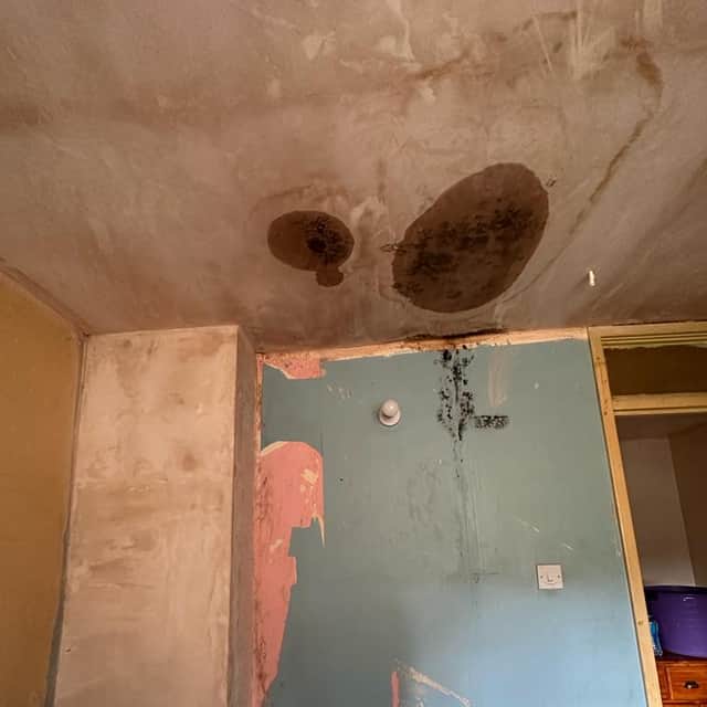 Pictured is the wall and ceiling in one of the bedrooms. A visible damp patch is on the ceiling, as well as mould stretching along the paintwork.
