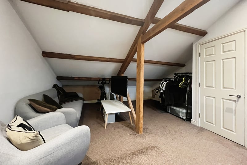 On the second floor is a large bedroom spanning the length of the house with exposed wood beams.