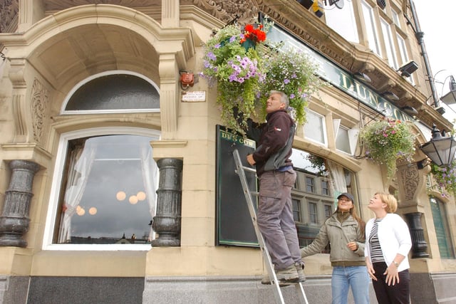 Licensee Carmel Scott, right, was given a hand to put up hanging baskets from Lindsay Chapman and Vic James in 2004.