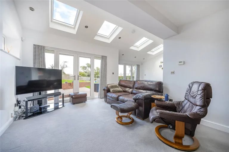The impressive living, dining and kitchen area features Velux rooflights and French doors to the rear garden.
