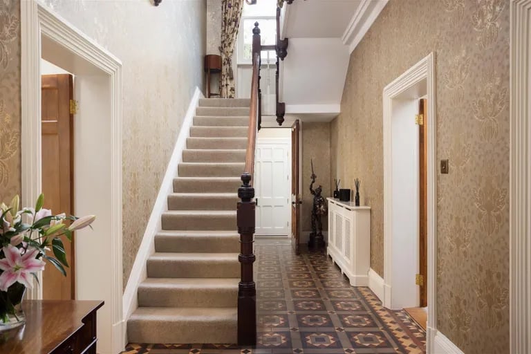 The grand hallway with original tiled floors and ornate coving.
