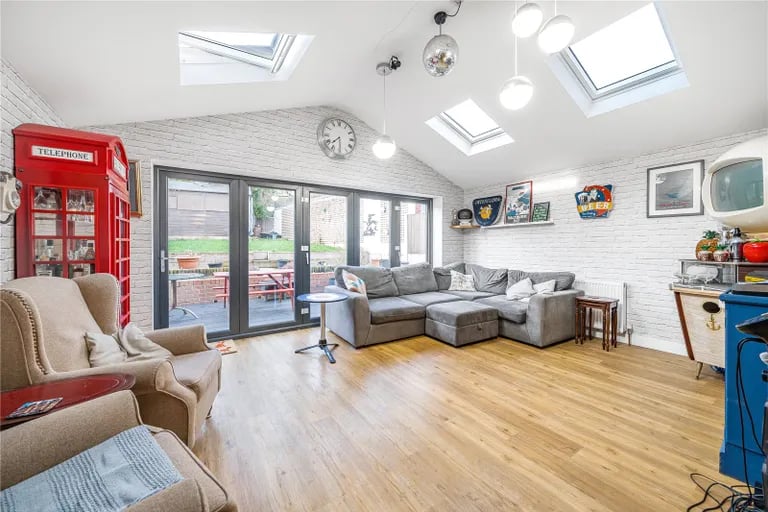 It leads to this large sitting room with bi-folding glass doors to the rear garden and rooflight windows.