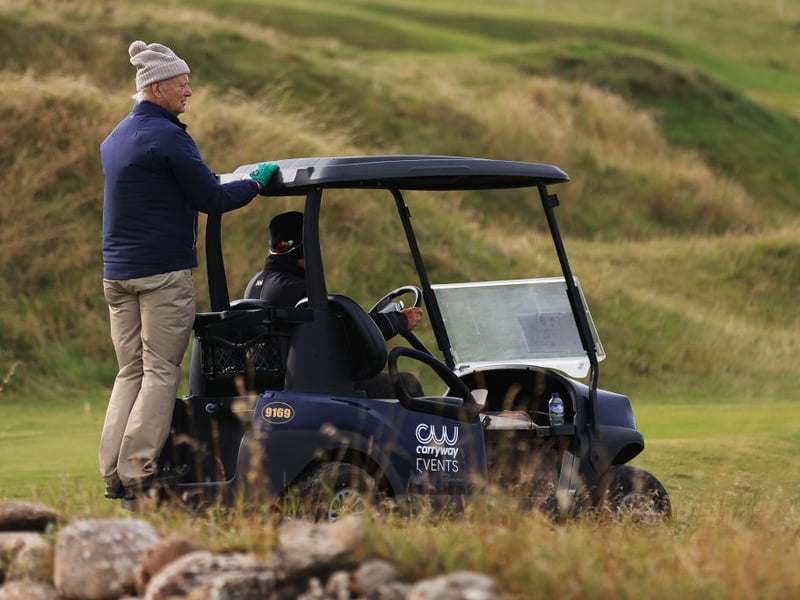 Ghostbusters actor Bill Murray hitches a lift on a caddy car.