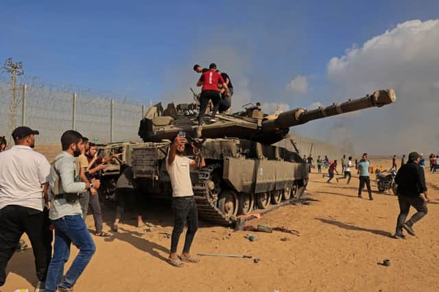 Palestinians take control of an Israeli tank after crossing the border fence with Israel from Khan Yunis in the southern Gaza Strip on October 7, 2023. Credit: AFP via Getty Images
