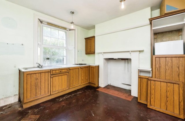 The kitchen has the original floors and fireplace.