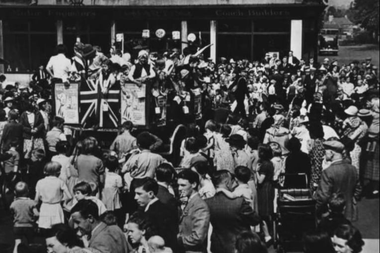 A ‘Charities Day’ in Kirkintilloch (circa.1940) to raise funds and provision for the nearby Glasgow Royal Infirmary, where many wounded soldiers and people injured in the Blitz were being treated. Emblematic of the time, one performer on the stand can be seen in ‘blackface’ - a racist caricature harkening to America’s Jim Crow culture which mocked and ridiculed African-Americans for the entertainment of white audiences. The laws in America affirming black people as second class citizens were in place well up until 1965.
