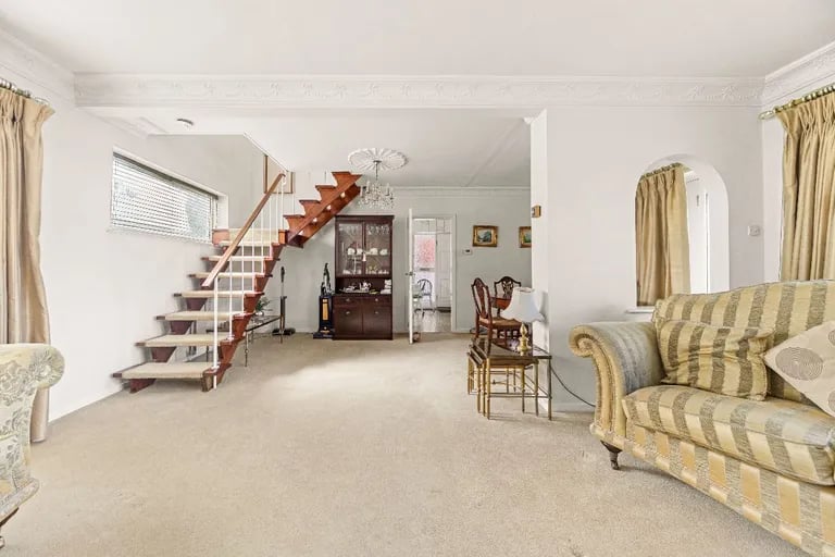 The bright living room has stairs to the first floor.